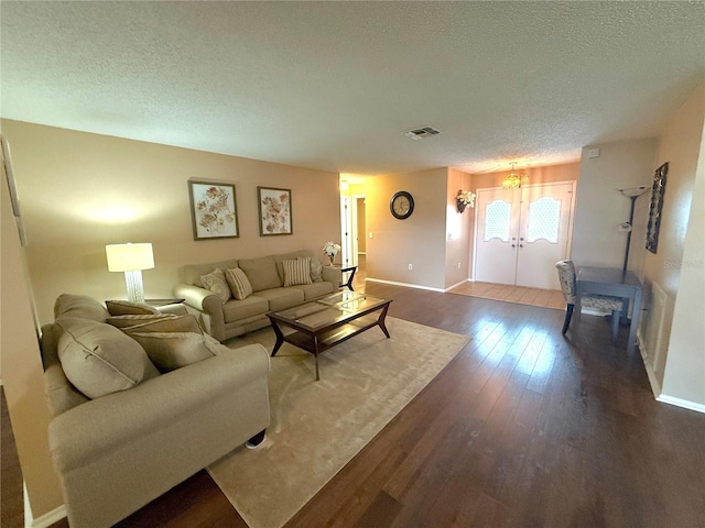 living room with hardwood / wood-style floors, french doors, and a textured ceiling