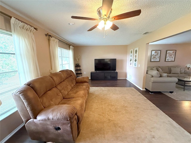 living room with ceiling fan, dark hardwood / wood-style floors, and a textured ceiling