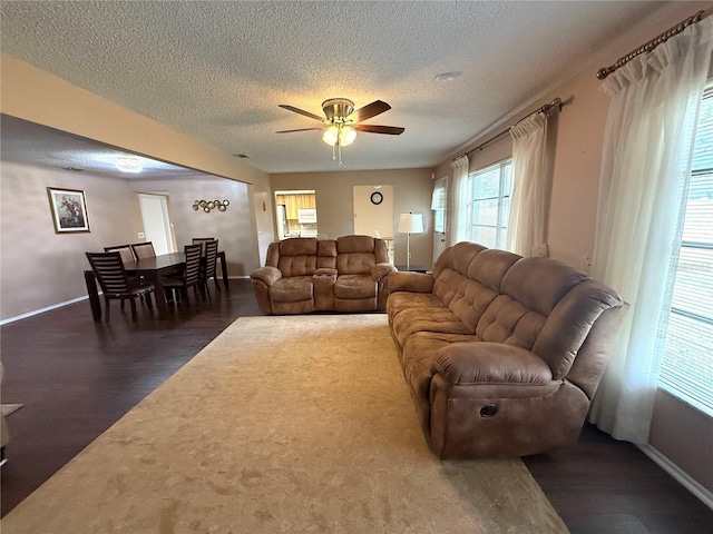 living room featuring ceiling fan, a textured ceiling, and dark hardwood / wood-style flooring