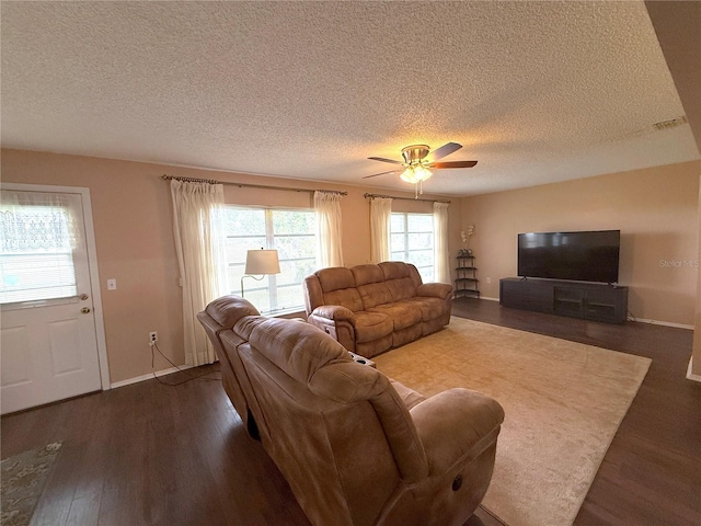 living room with dark wood-type flooring, ceiling fan, and a textured ceiling