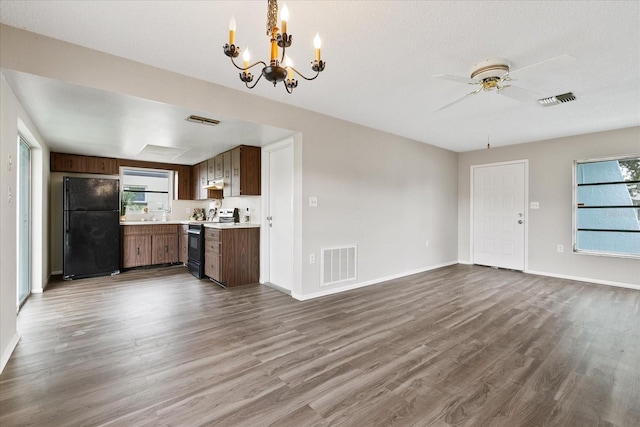 kitchen featuring black refrigerator, stainless steel electric stove, wood-type flooring, a textured ceiling, and ceiling fan with notable chandelier