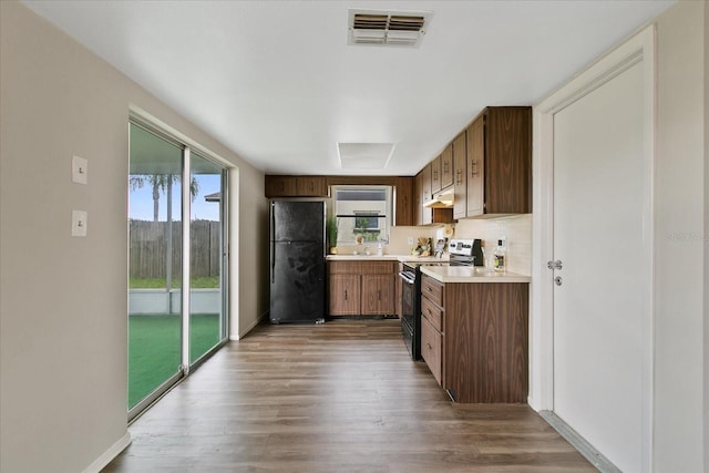 kitchen with electric stove, black refrigerator, and wood-type flooring