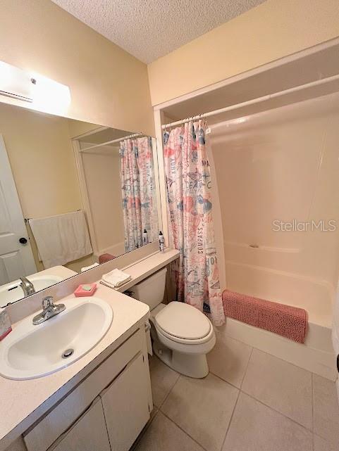 full bathroom featuring toilet, shower / bathtub combination with curtain, tile patterned floors, a textured ceiling, and vanity