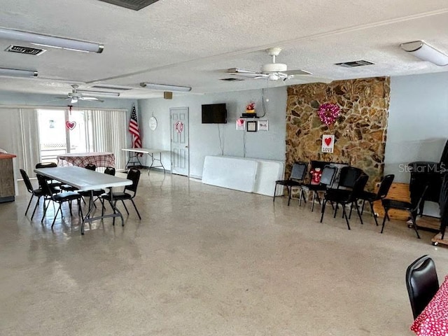 dining area featuring ceiling fan and a textured ceiling