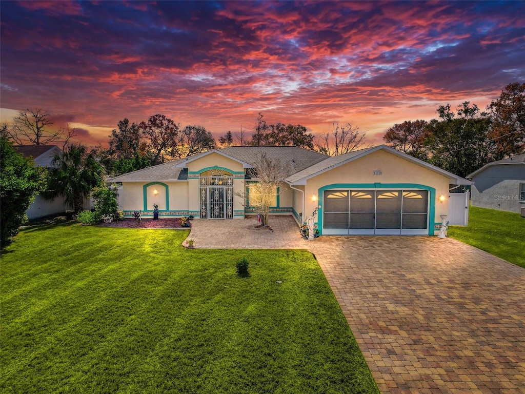 ranch-style house with a garage and a lawn