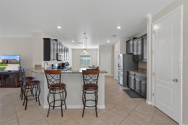 kitchen with appliances with stainless steel finishes, light tile patterned flooring, light stone countertops, a peninsula, and a kitchen bar