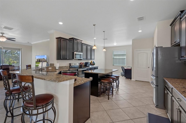 kitchen with stainless steel appliances, a sink, visible vents, and a kitchen breakfast bar