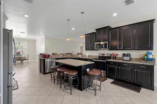 kitchen featuring a peninsula, appliances with stainless steel finishes, visible vents, and dark cabinets