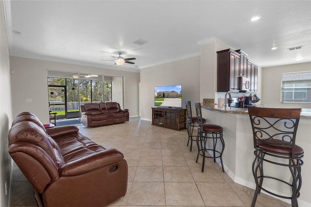 living room featuring a ceiling fan, a wealth of natural light, visible vents, and light tile patterned floors