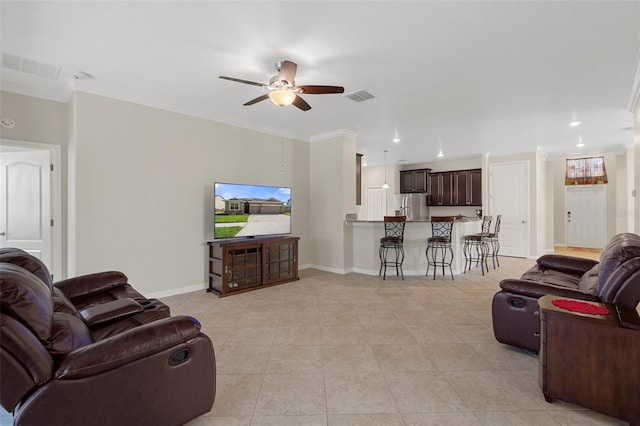 living area featuring light tile patterned floors, a ceiling fan, visible vents, baseboards, and crown molding