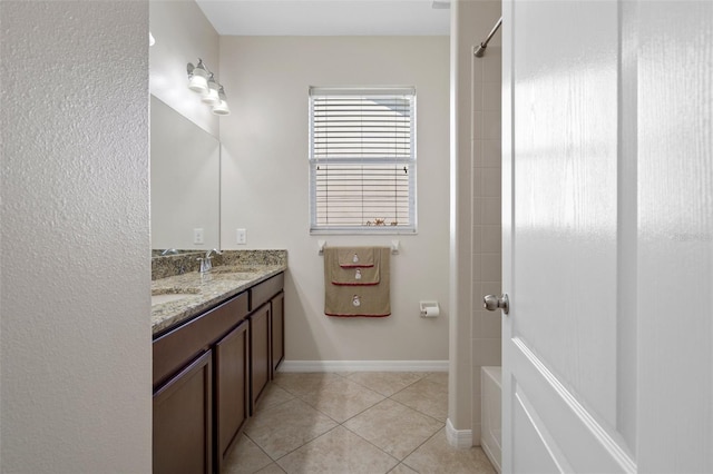 bathroom with shower / bathtub combination, tile patterned flooring, a sink, baseboards, and double vanity