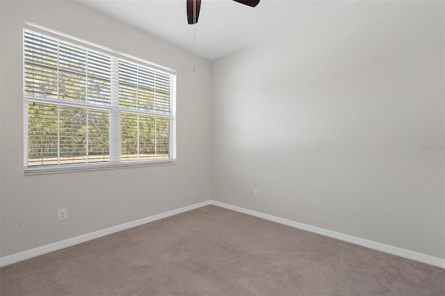 carpeted empty room featuring a ceiling fan and baseboards