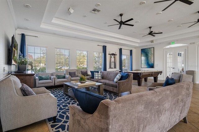 living room featuring french doors, a tray ceiling, plenty of natural light, and visible vents