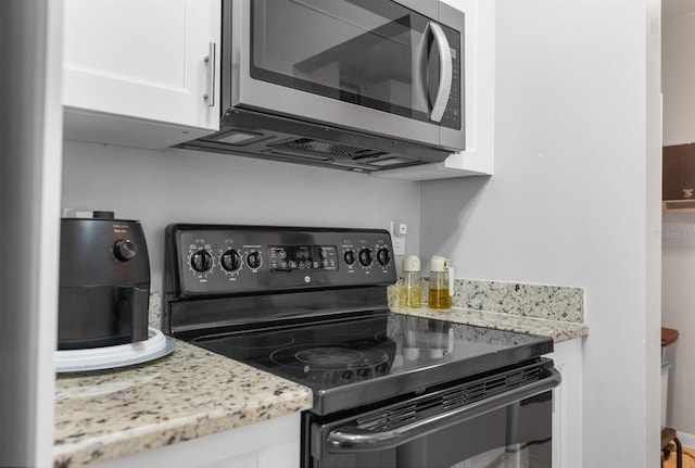 kitchen featuring white cabinetry, black range with electric stovetop, and light stone countertops