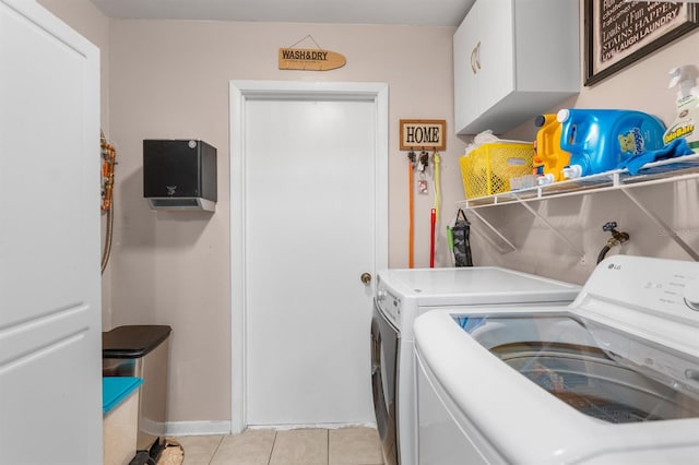 laundry area featuring cabinets, light tile patterned floors, and washing machine and dryer