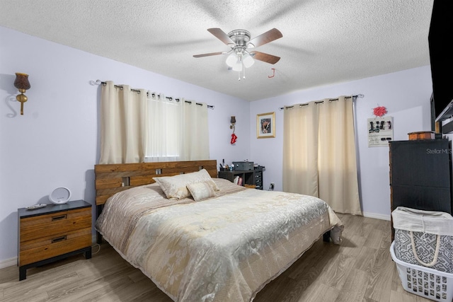 bedroom with ceiling fan, light hardwood / wood-style floors, and a textured ceiling