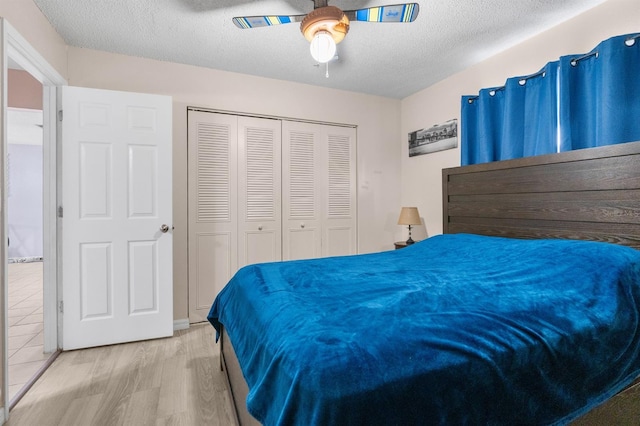 bedroom with a textured ceiling, ceiling fan, a closet, and wood-type flooring