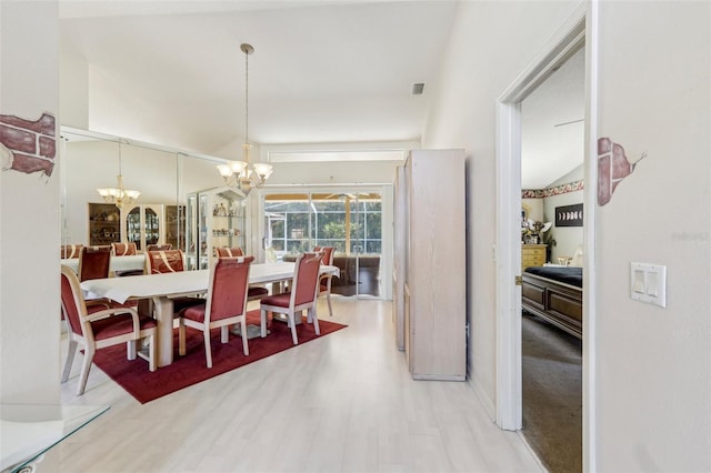 dining room with vaulted ceiling, a chandelier, and wood-type flooring