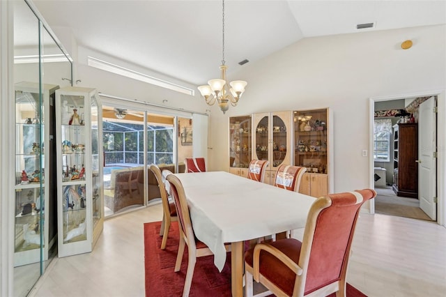 dining room with light hardwood / wood-style flooring, a chandelier, and vaulted ceiling