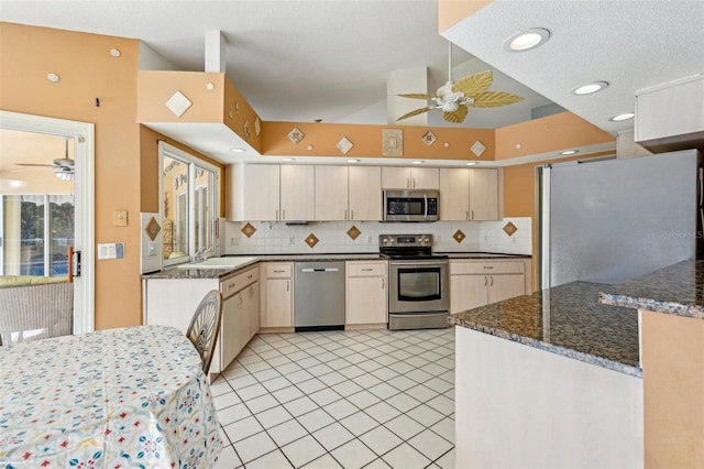 kitchen featuring sink, backsplash, appliances with stainless steel finishes, and dark stone counters