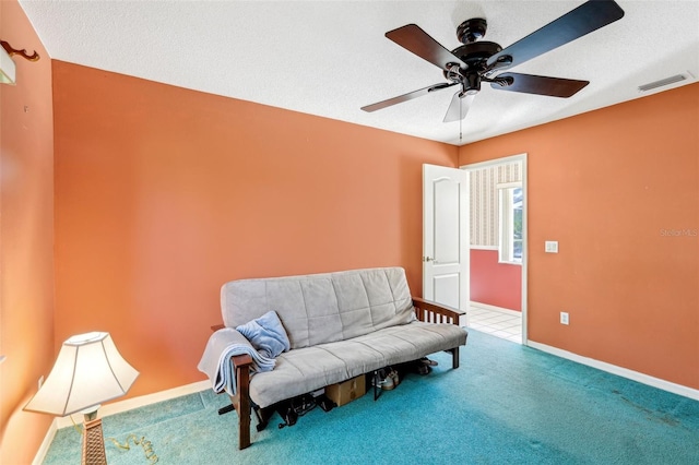 living area with ceiling fan, a textured ceiling, and carpet flooring