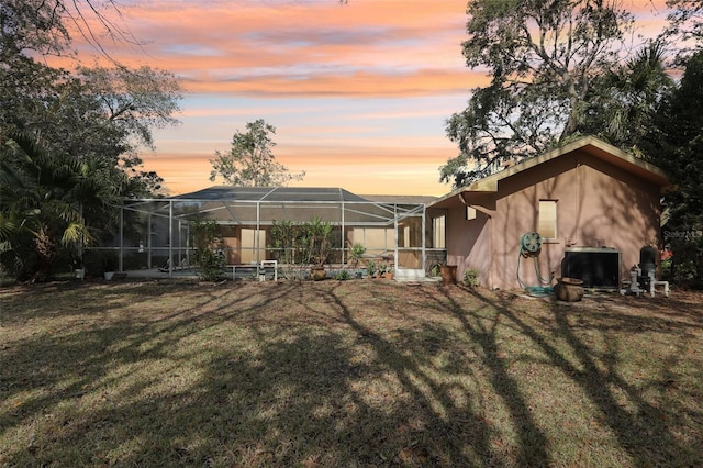 yard at dusk featuring glass enclosure and central air condition unit