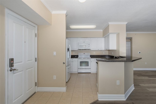 kitchen with white appliances, white cabinets, ornamental molding, and kitchen peninsula