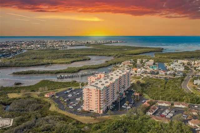 aerial view at dusk featuring a water view