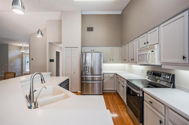 kitchen with visible vents, pendant lighting, a sink, stainless steel appliances, and light countertops