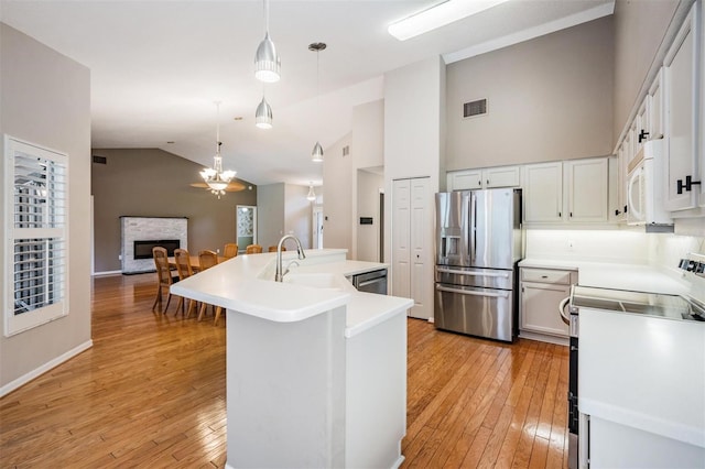 kitchen with visible vents, an island with sink, a fireplace, stainless steel appliances, and a sink