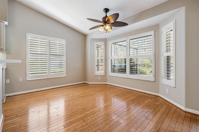 empty room with lofted ceiling, light wood-style floors, a healthy amount of sunlight, and a ceiling fan