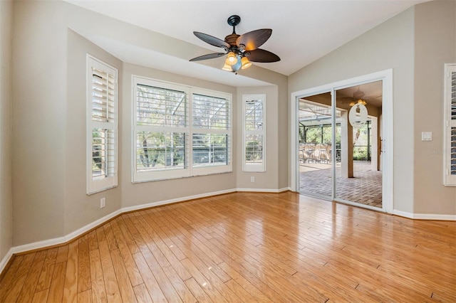 spare room featuring a ceiling fan, vaulted ceiling, baseboards, and light wood-type flooring