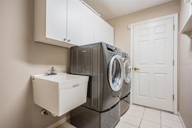 laundry room with washer and clothes dryer, cabinet space, light tile patterned flooring, and a sink