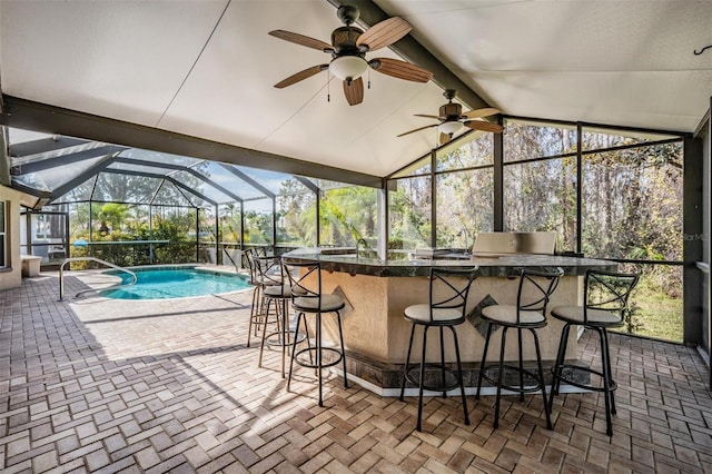 outdoor pool with an outdoor kitchen, outdoor wet bar, ceiling fan, a lanai, and a patio area