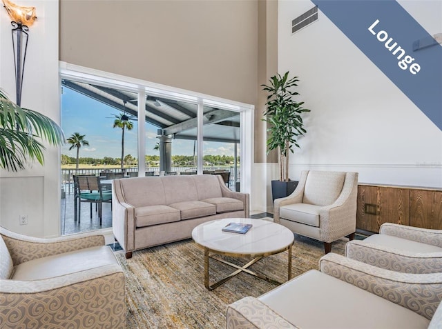 living area featuring a wainscoted wall and a towering ceiling