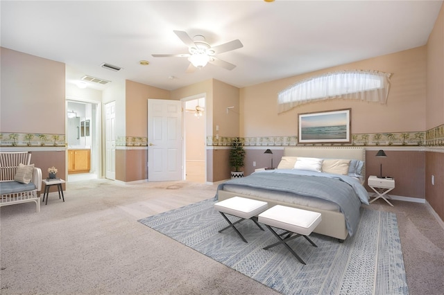 bedroom featuring light carpet, visible vents, ensuite bath, and ceiling fan