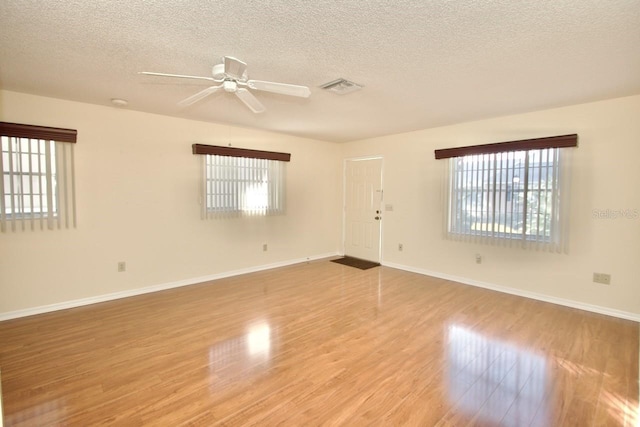 spare room with a textured ceiling, ceiling fan, and light hardwood / wood-style flooring