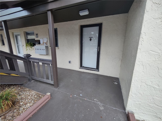 doorway to property featuring a porch and stucco siding