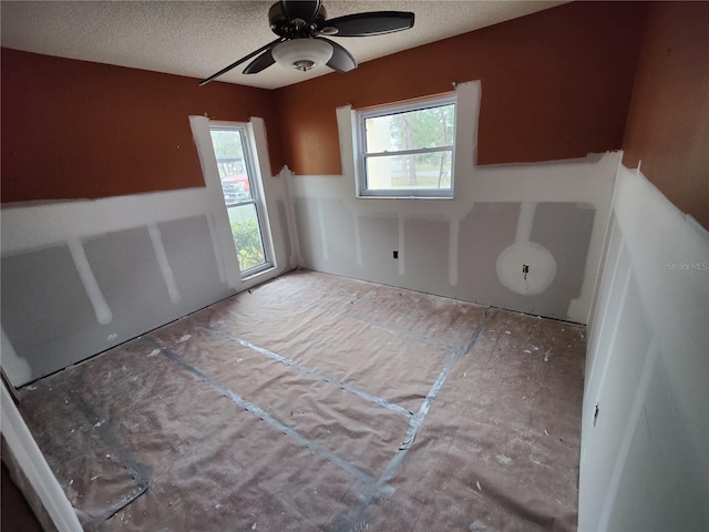 unfurnished room with a ceiling fan and a textured ceiling