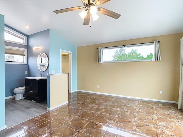 interior space with ceiling fan, toilet, vanity, and lofted ceiling