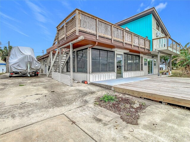 rear view of house featuring a balcony and a wooden deck