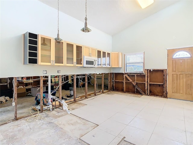 kitchen featuring light brown cabinetry, high vaulted ceiling, and hanging light fixtures