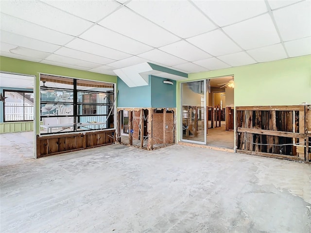 unfurnished living room featuring concrete floors and a paneled ceiling