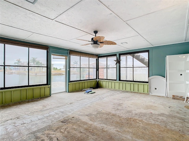 unfurnished sunroom with ceiling fan and a water view