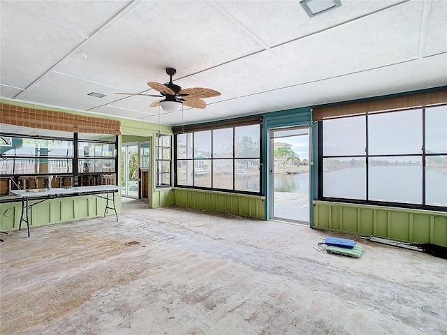 unfurnished sunroom featuring a water view and ceiling fan