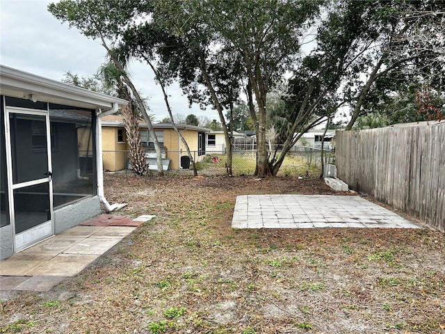 view of yard with a patio, a fenced backyard, and a sunroom