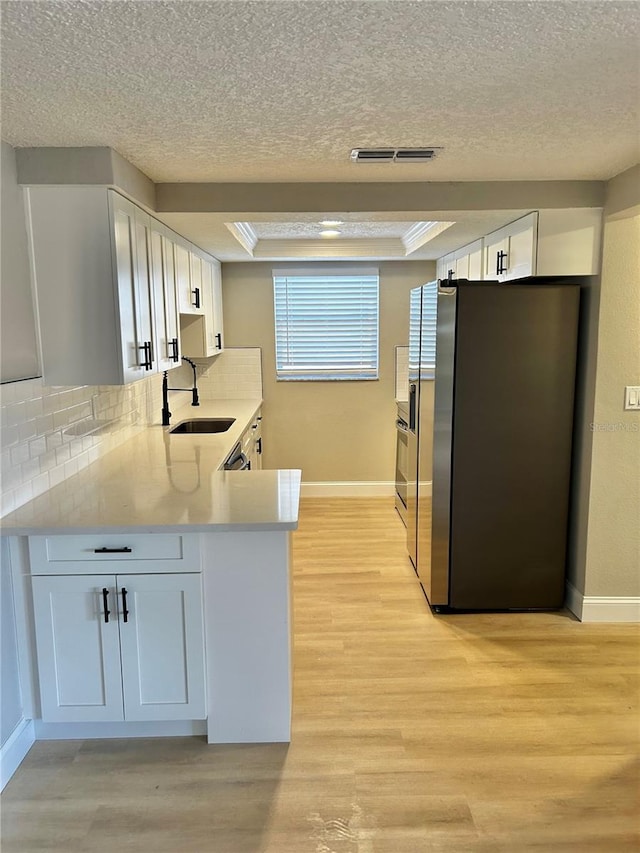 kitchen with visible vents, a sink, freestanding refrigerator, and light wood-style floors