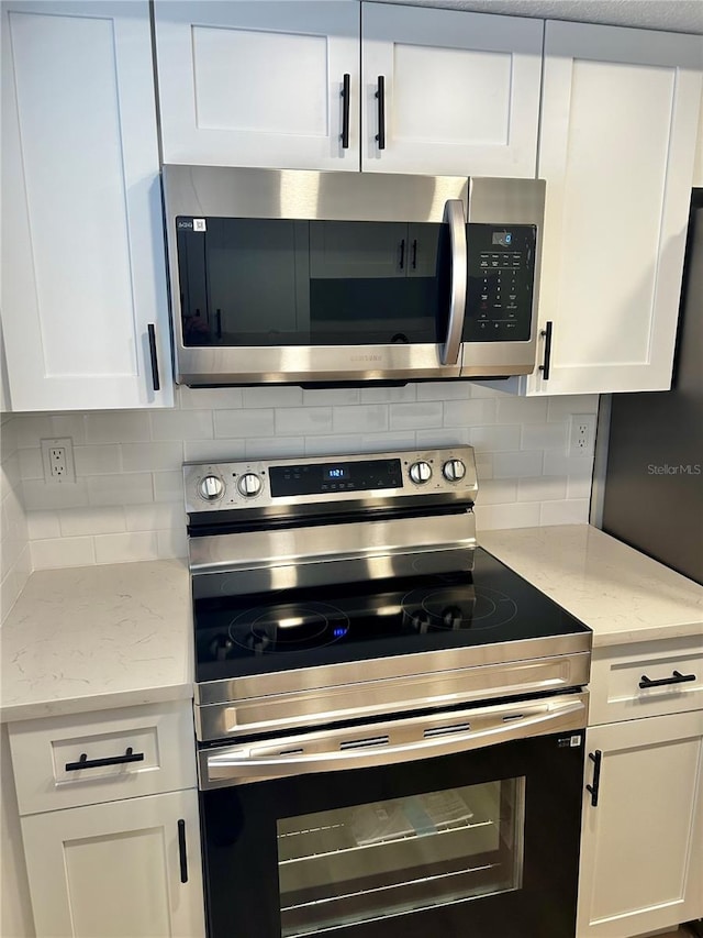 kitchen with stainless steel appliances, white cabinets, backsplash, and light stone countertops