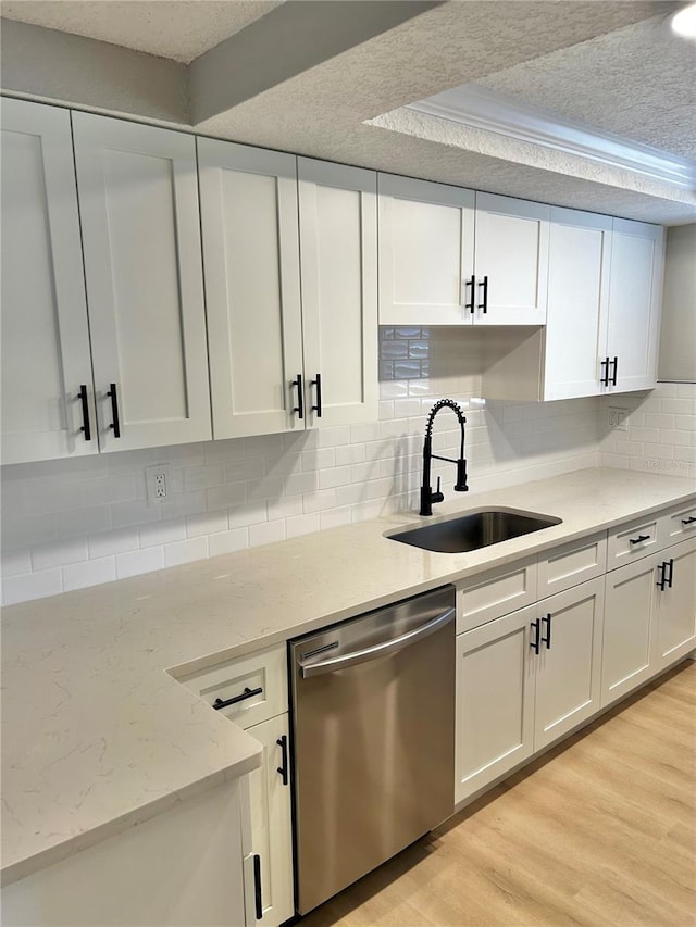 kitchen featuring light wood-style floors, white cabinets, a sink, a textured ceiling, and dishwasher