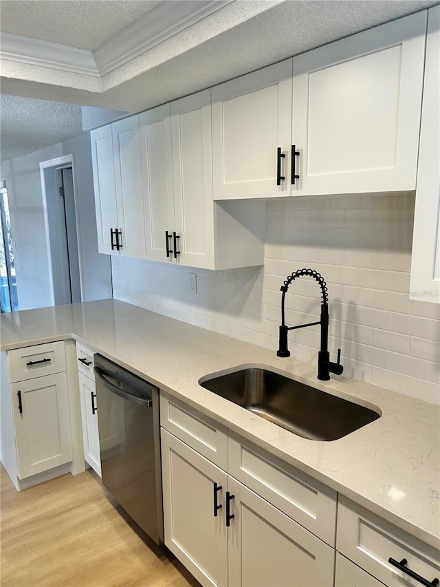 kitchen featuring dishwasher, a textured ceiling, a sink, and white cabinetry